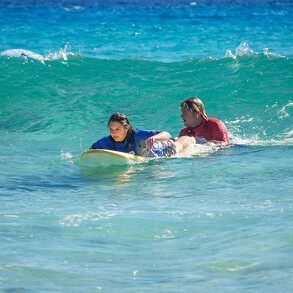 Surf teacher pushes surfing students into the waves